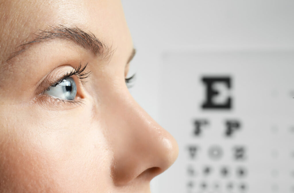 A close-up of a woman's face, with a Snellen eye chart in the background